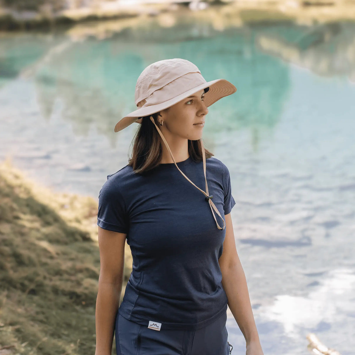 Dame mit hellem Sonnenhut in den Bergen am See, atmungsaktiver Outdoor Sonnenhut Damen für Sommerwanderungen.