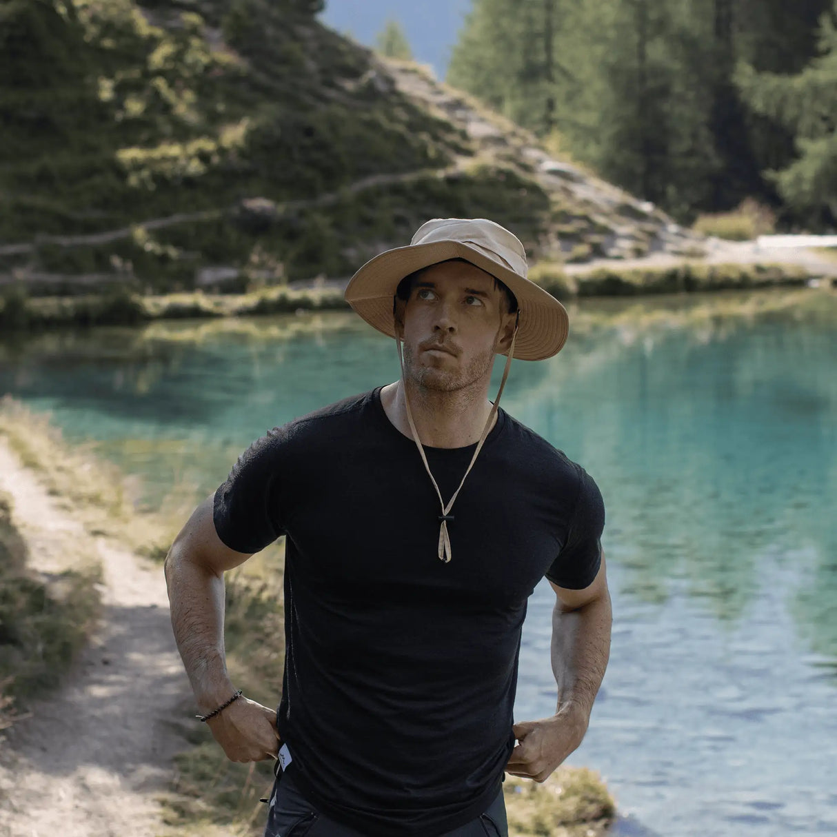 Mann trägt Sonnenhut beim Wandern am See, leichter Outdoor Sonnenhut Herren für Trekking, Reisen und Sonnenschutz.