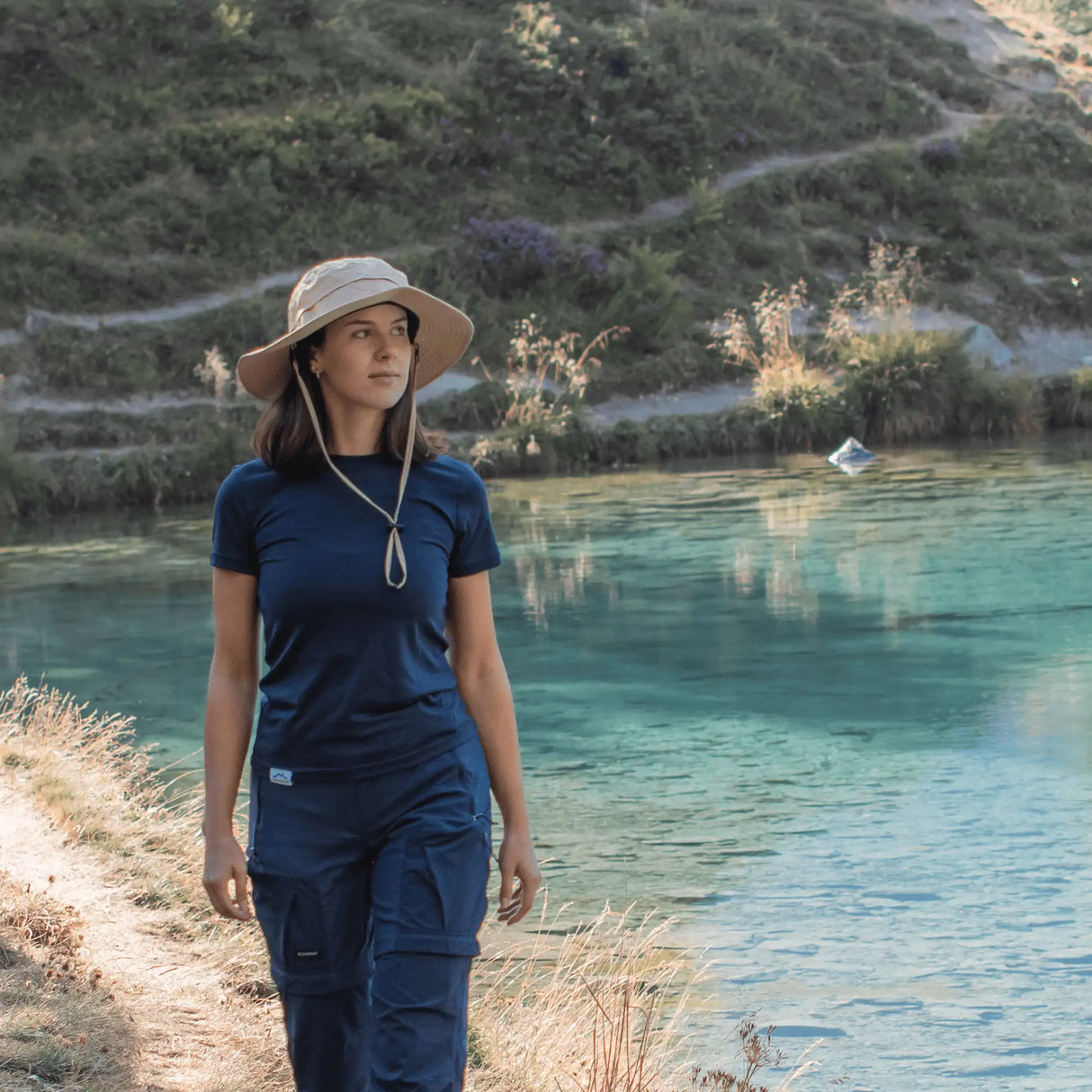 Wanderin mit Sonnenhut in den Bergen, Outdoor Sonnenhut Damen mit Kinnband für sicheren Halt und Sonnenschutz.