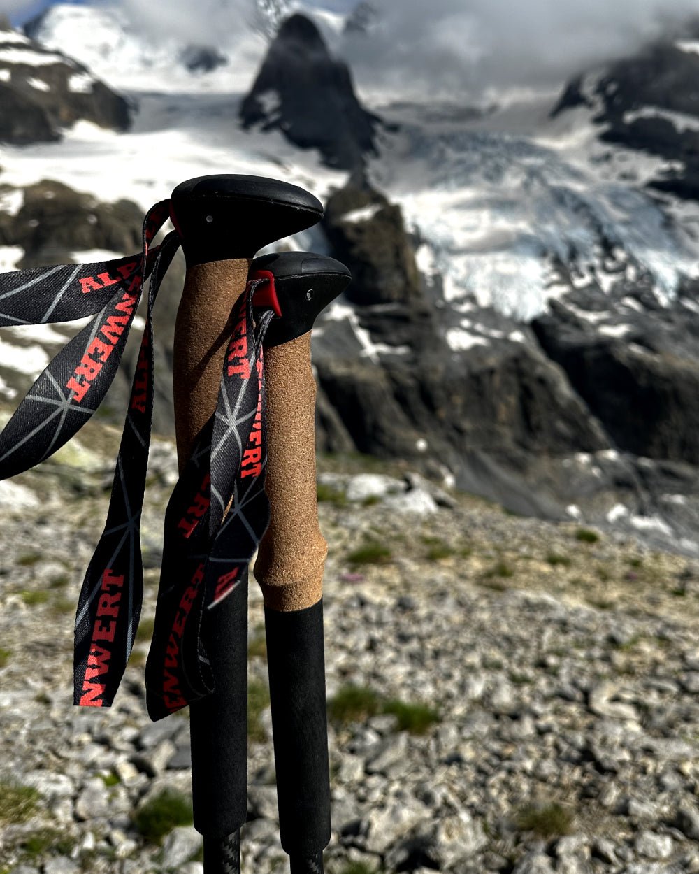 Zwei Alpenwert Teleskop-Wanderstöcke mit Korkgriff stehen im Geröll vor einem Gletscher