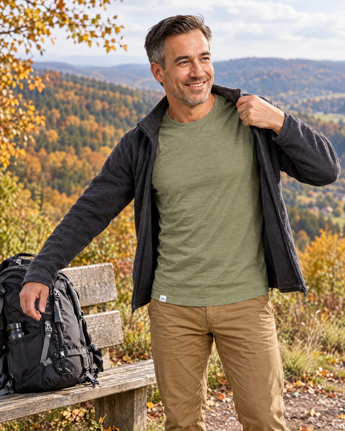 Wanderer im grünen Merino Shirt an einer Bank am Weg