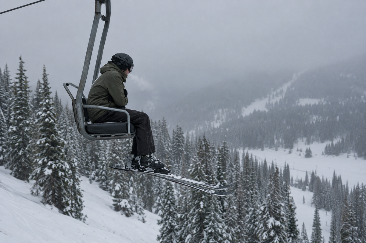 Skifahrer sitzt an einem kalten Morgen im Sessellift