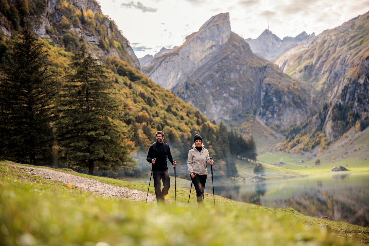 Paar mit Wanderstöcken auf einem Uferweg am Seealpsee im Herbst